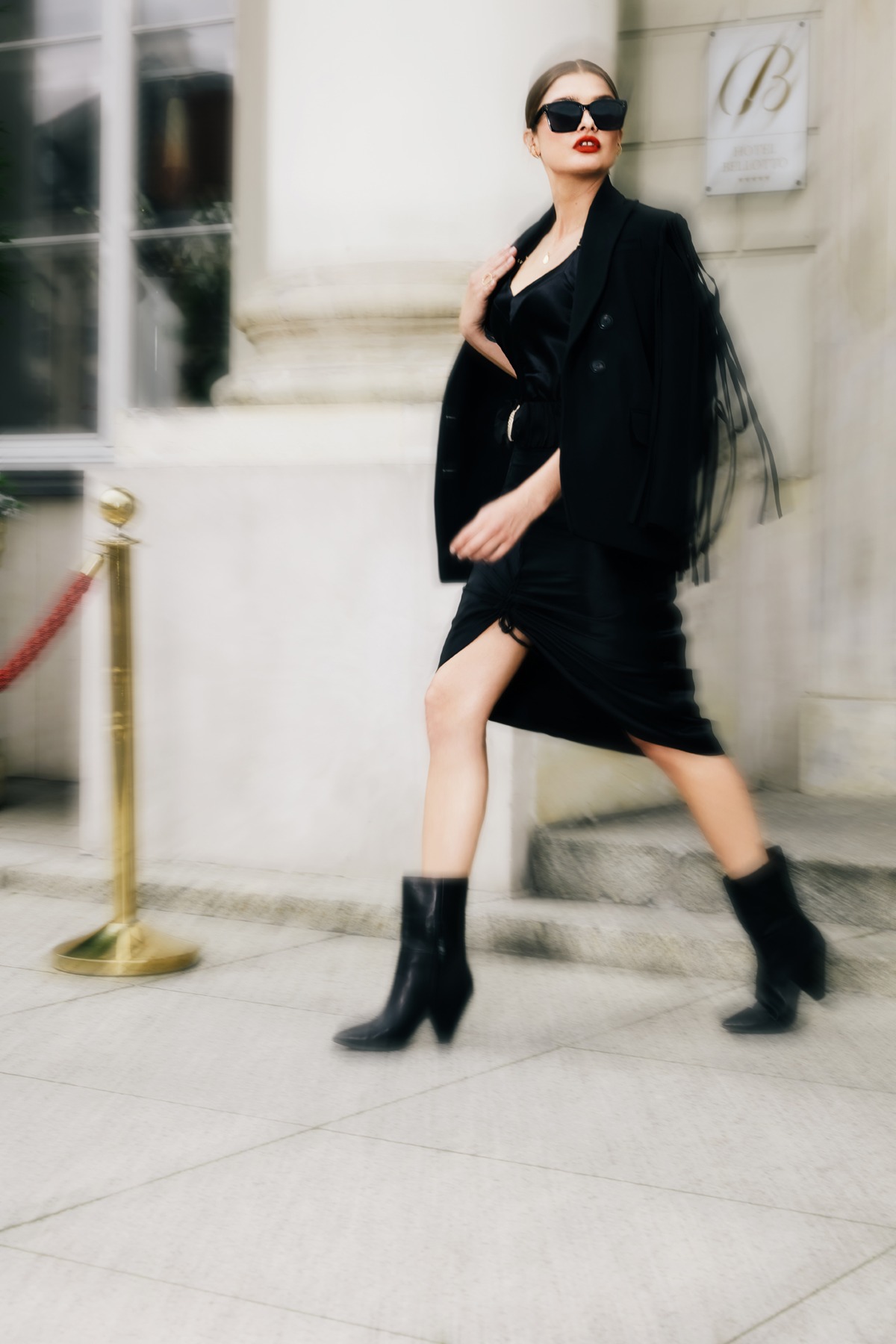 Bilquiis campaign: woman in a black dress and fringed jacket walking confidently